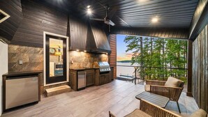 Una cocina moderna con horno y parrilla integrados, un comedor con mobiliario de mimbre y vistas al exterior.