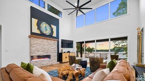 Una sala de estar moderna con chimenea de piedra, sofás de cuero y un ventanal con vistas panorámicas.