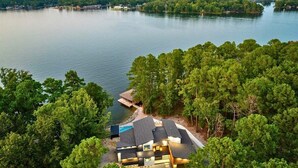 Propiedad junto al lago con una casa moderna, muelle y bosque circundante.