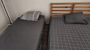 Two single beds with wooden headboards, grey bedding, and a patterned pillow on one bed. - Appartement Rénové Avec Place de Parking Dans Résidence Fermée et Sécurisée (Gières)