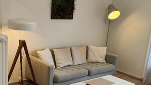 A modern living room with a grey sofa, a white coffee table, and a floor lamp. - Appartement Rénové Avec Place de Parking Dans Résidence Fermée et Sécurisée (Gières)