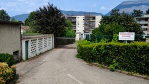 A gated entrance to a residential area with a sign reading "PROPRIETE PRIVEE" and a mountain in the background. - Appartement Rénové Avec Place de Parking Dans Résidence Fermée et Sécurisée (Gières)