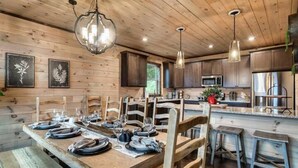 Une table à manger en bois, dressée avec des assiettes et des verres, entourée de chaises en bois.
