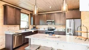 Une cuisine moderne avec des meubles en bois, des appareils en acier inoxydable et un grand îlot central doté de tabourets.