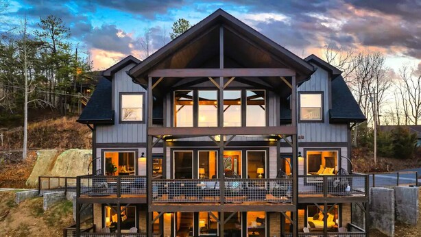 Une maison à plusieurs étages, dotée d’un balcon à chaque niveau, de grandes fenêtres et d’une terrasse en bois.