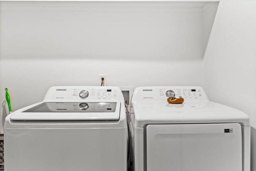 Two white Samsung washing machines in a laundry room with a green pen on the left.