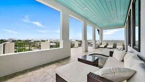 A spacious balcony with a view of the city skyline, featuring a seating area with cushions and a coffee table.