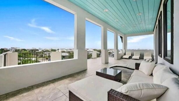 Un balcón amplio con vistas al horizonte de la ciudad, que incluye una zona de estar con cojines y una mesa de centro.