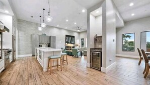 A spacious kitchen with wooden flooring, a central island, and bar stools.