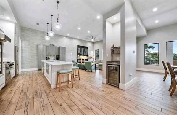 A spacious kitchen with wooden flooring, a central island, and bar stools.
