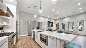 Una cocina moderna con una isla grande, gabinetes grises y suelo de madera.