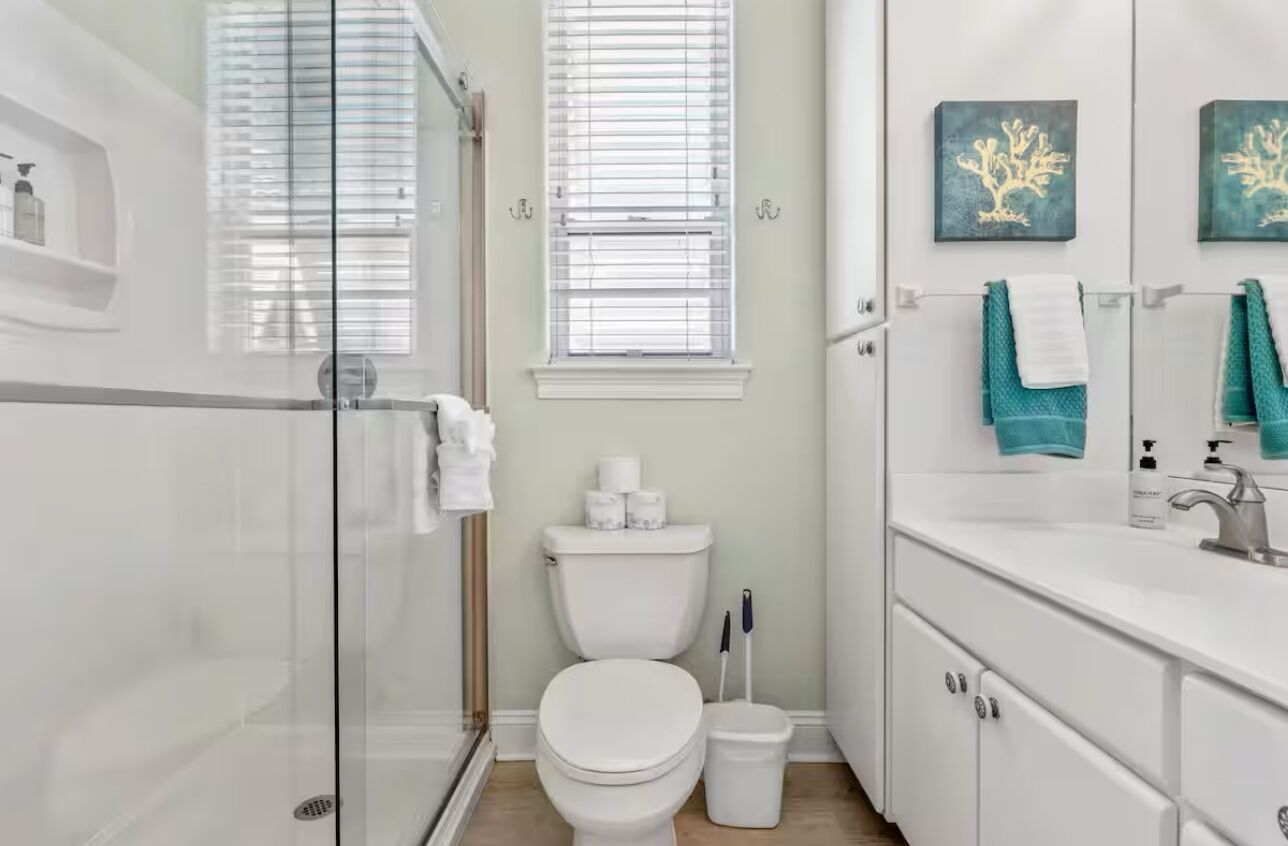 A modern bathroom with a glass shower enclosure, a toilet, and a vanity with a sink and towel rack.