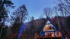 Une cabane dotée d’une grande façade vitrée, entourée d’arbres.