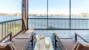 A balcony with a view of the water, wicker furniture, and a table with a candle. - Waterfront Villa-Pool-King Bed-Steps to the Sand! (Destin)