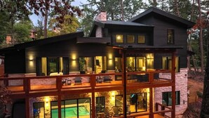 A multi-story modern house with a pool, large windows, and a deck area.