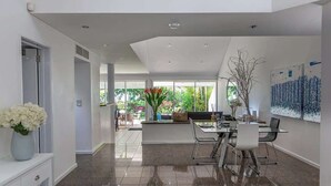 A modern kitchen with a dining area, large windows, and a view of the outdoors. - Port Douglas Mirage Villa#423 (Port Douglas)