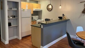Une cuisine compacte dotée d’un îlot central intégré, de meubles de rangement en bois et d’un coin repas avec une table et des chaises.
