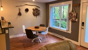 Un coin repas avec une table ronde en bois, deux chaises noires et un canapé en cuir marron.