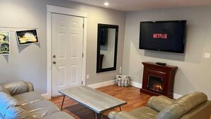 A living room with two leather sofas, a coffee table, a fireplace, a TV, and artwork on the walls. - Sienna's Tree House #3 (Tofino)