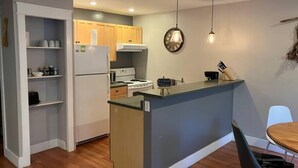 A modern kitchen with wooden cabinets, a built-in island, and pendant lighting. - Sienna's Tree House #3 (Tofino)