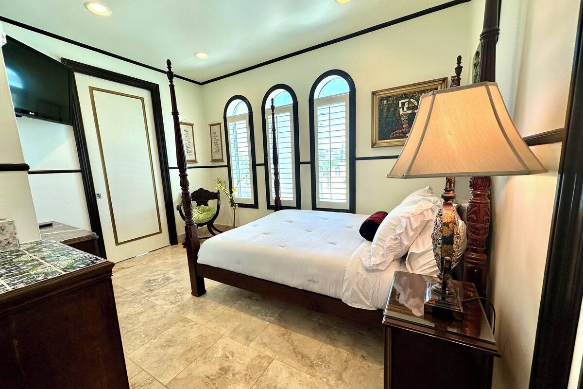 A bedroom with a large bed, a nightstand, a chair, and a television.