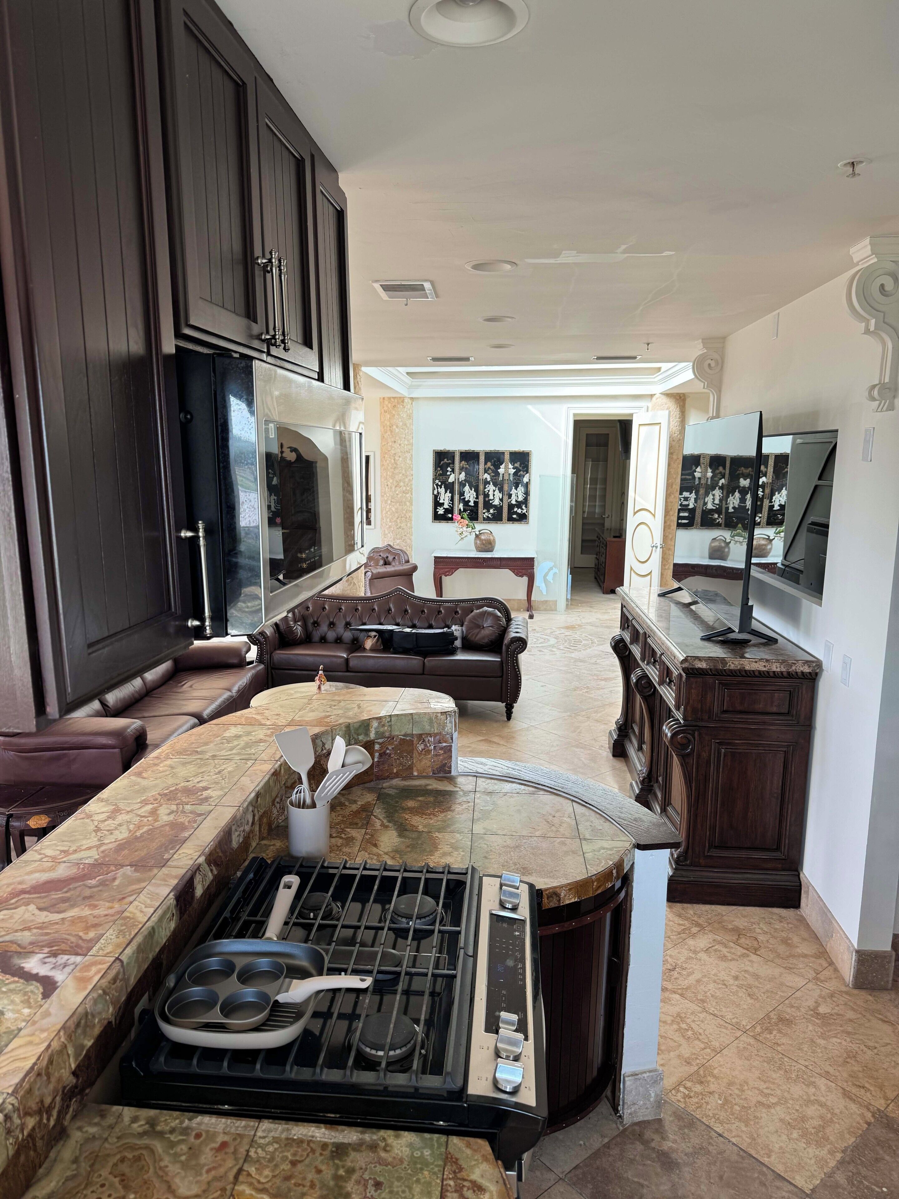 A kitchen with a built-in stove, a dining area with a sofa, and a TV on a stand.
