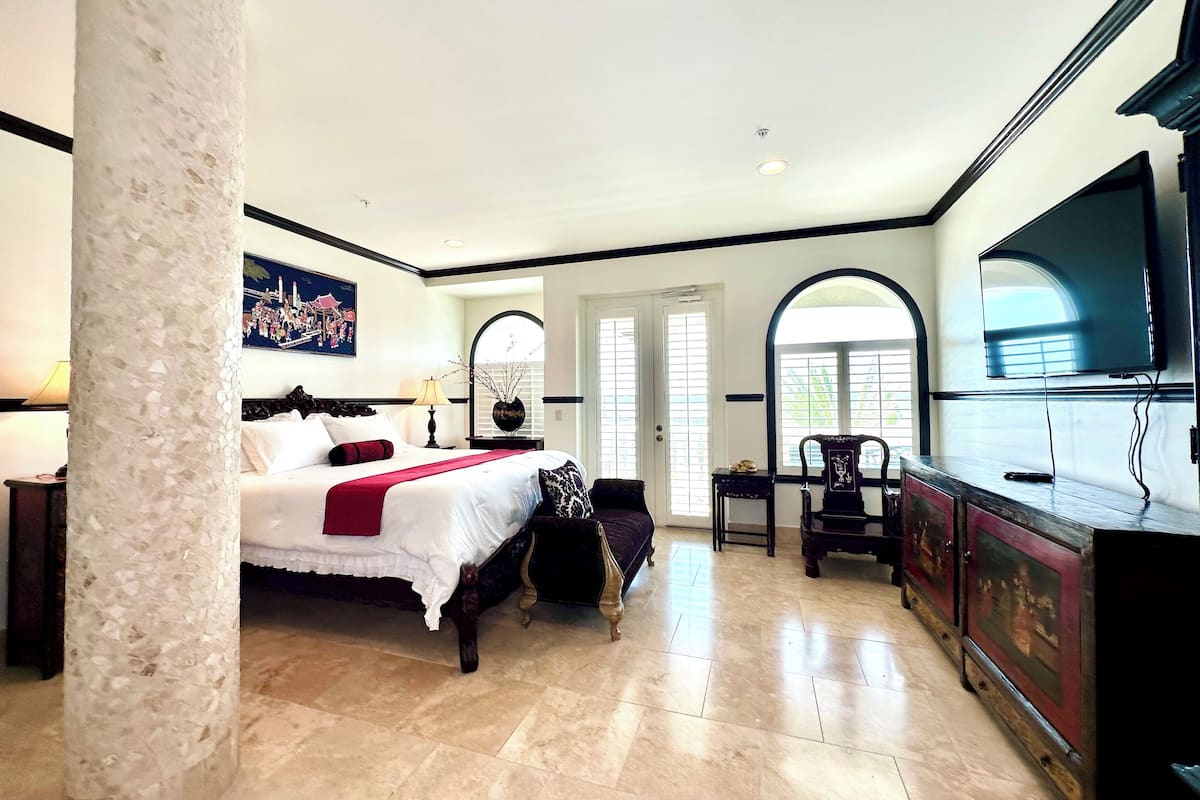 A spacious bedroom with a large bed, a television, and a desk area.