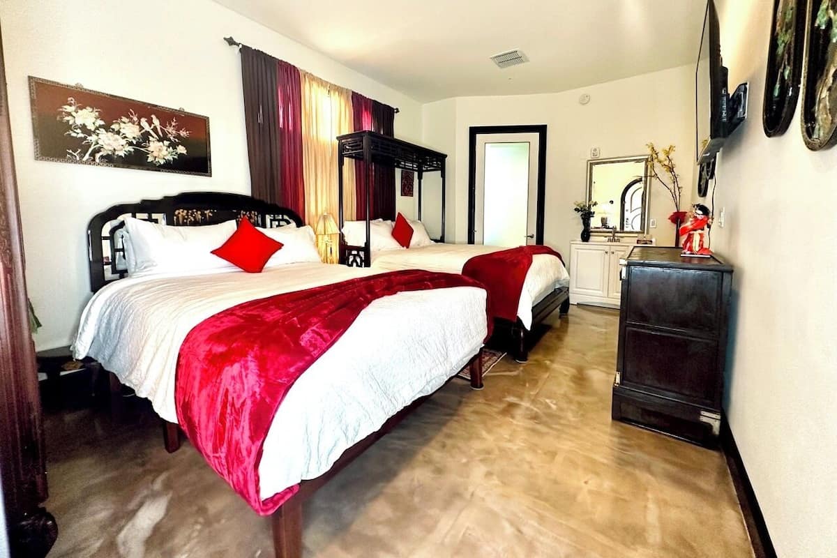 A hotel room with two beds, a dresser, and a mirror.