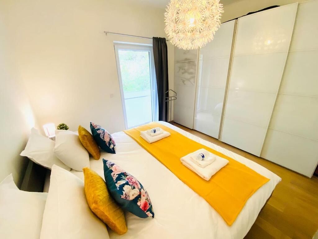 Een hotelkamer met een bed, een gele loper en een groot raam.