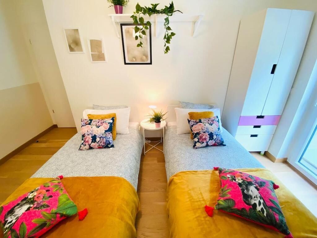 Une chambre avec deux lits, une petite table avec une plante et une armoire.