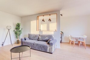 Relax in a spacious living area with a sofa, dining table, and potted plant.