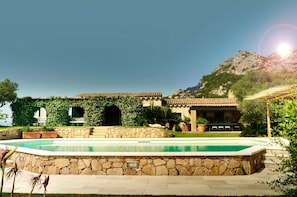 A pool with stone walls, a building with a tiled roof, and a mountain in the background. - Villa 'Acula' with Sea View, Wi-Fi and Air Conditioning (Cannigione)