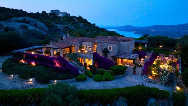 A large, two-story house with a stone facade, surrounded by landscaped gardens and a view of the sea. - Villa 'Acula' with Sea View, Wi-Fi and Air Conditioning (Cannigione)