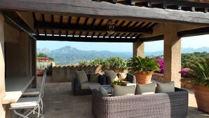 An outdoor patio with wicker furniture, potted plants, and a view of mountains. - Villa 'Acula' with Sea View, Wi-Fi and Air Conditioning (Cannigione)