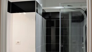 A modern bathroom with a glass-enclosed shower, a white sink, and a toilet. - Luxury Vatican Rooms (Rome)