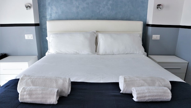 A neatly made bed with white linens and two towels placed at the foot of the bed. - Luxury Vatican Rooms (Rome)
