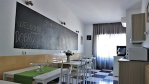 A modern kitchen with a chalkboard wall, white furniture, and a checkered floor. - Luxury Vatican Rooms (Rome)