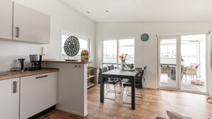 Een moderne keuken met witte kasten, een houten aanrechtblad en een eethoek met een zwarte tafel en stoelen.