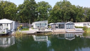 Een vakantiehuis aan het meer met moderne cabins, een steiger en een kleine tuin.
