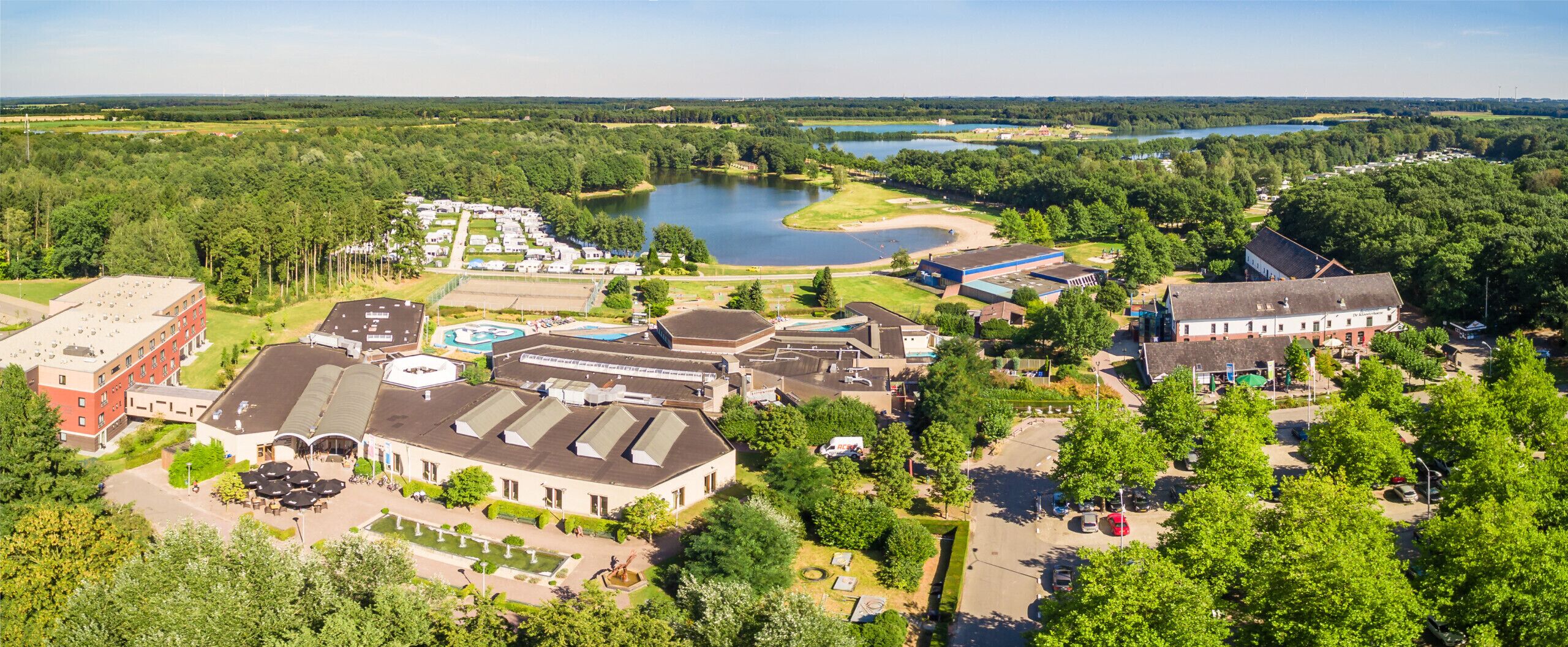 An aerial view of a resort with multiple buildings, a swimming pool, and a lake.