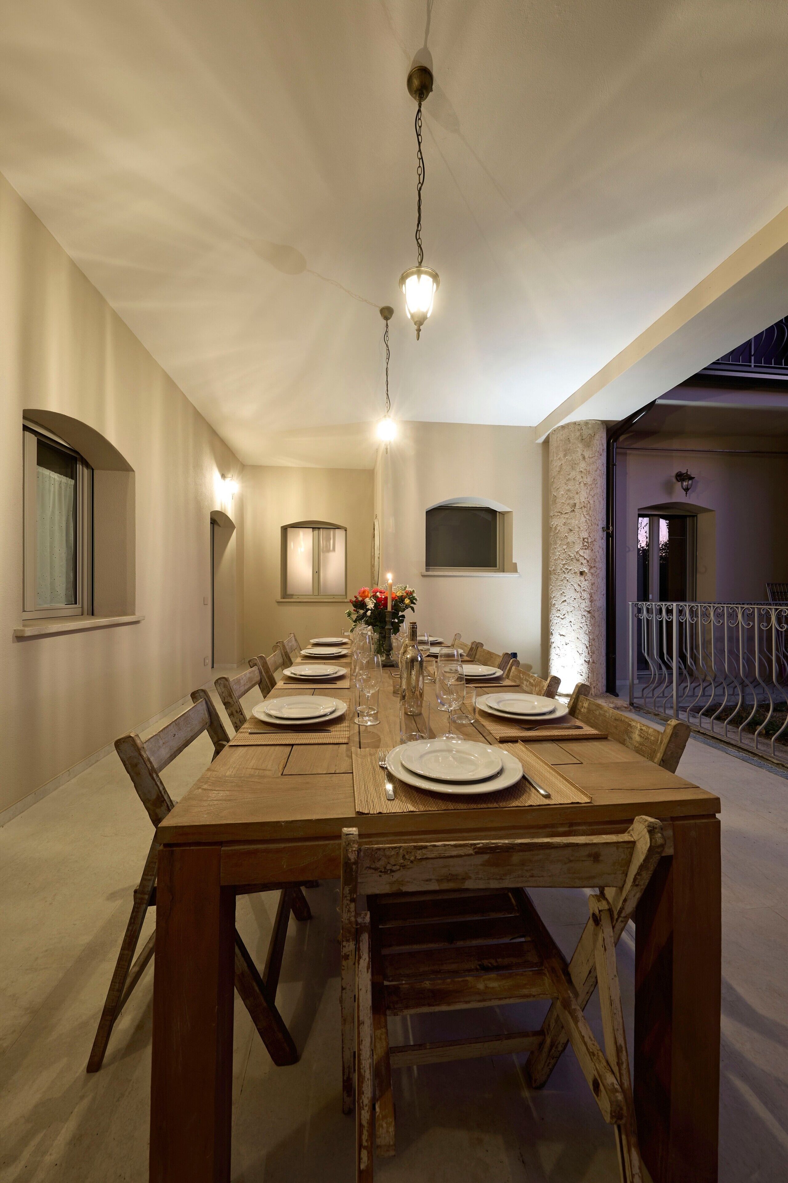 Uma sala de jantar com uma mesa de madeira comprida, cadeiras e um lustre.