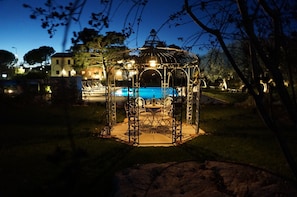 A gazebo with a pool in the background.