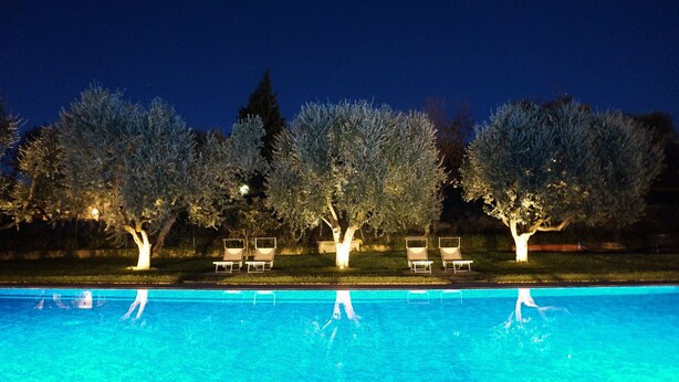 Una piscina con árboles y sillas de descanso.