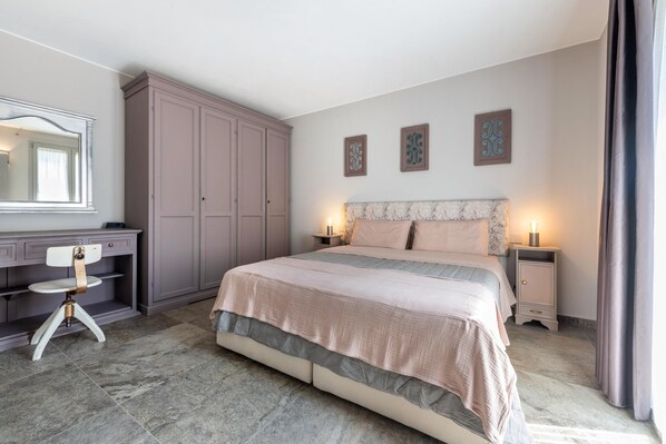 A bedroom with a bed, a vanity with a mirror, a wardrobe, and decorative wall art.