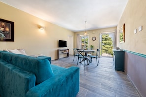 A living room with a sofa, TV, dining table, and chairs. - Apartment 'Abaye 4 Merlot - Charm' with Shared Pool, Wi-Fi and Air Conditioning (Soiano del Lago)