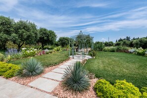 A garden with a gazebo, a pathway, and various plants.