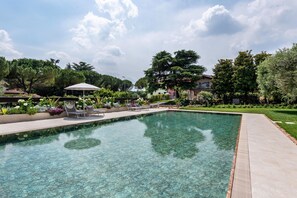 Une piscine aux eaux cristallines, dotée de chaises longues et d’un espace salon abrité.