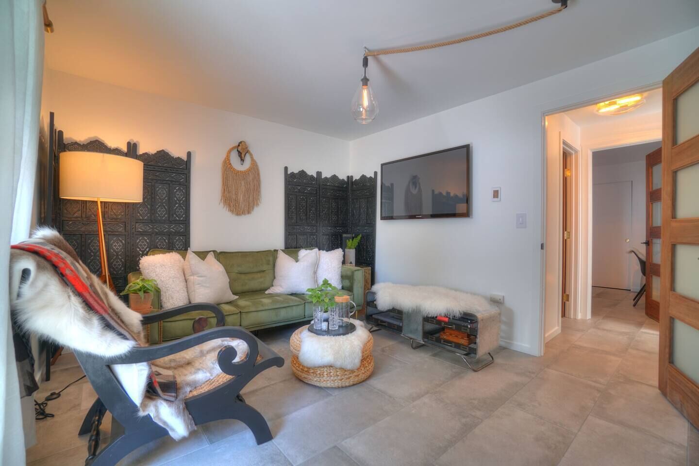 A cozy living room with a green sofa, a white armchair, and a small round table with decorative items.