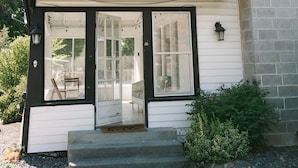 A two-story house with a covered porch, a chimney, and a small garden area. - The Kennewick Cottage  (Kennewick)