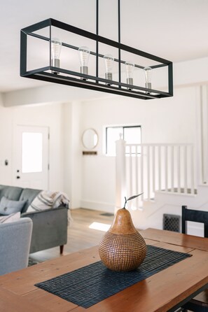 Un coin repas avec une table en bois, un vase décoratif et un luminaire suspendu.